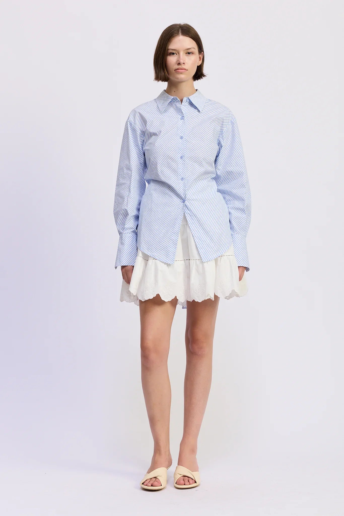 Woman wearing a light blue checkered shirt and white skirt on a white background