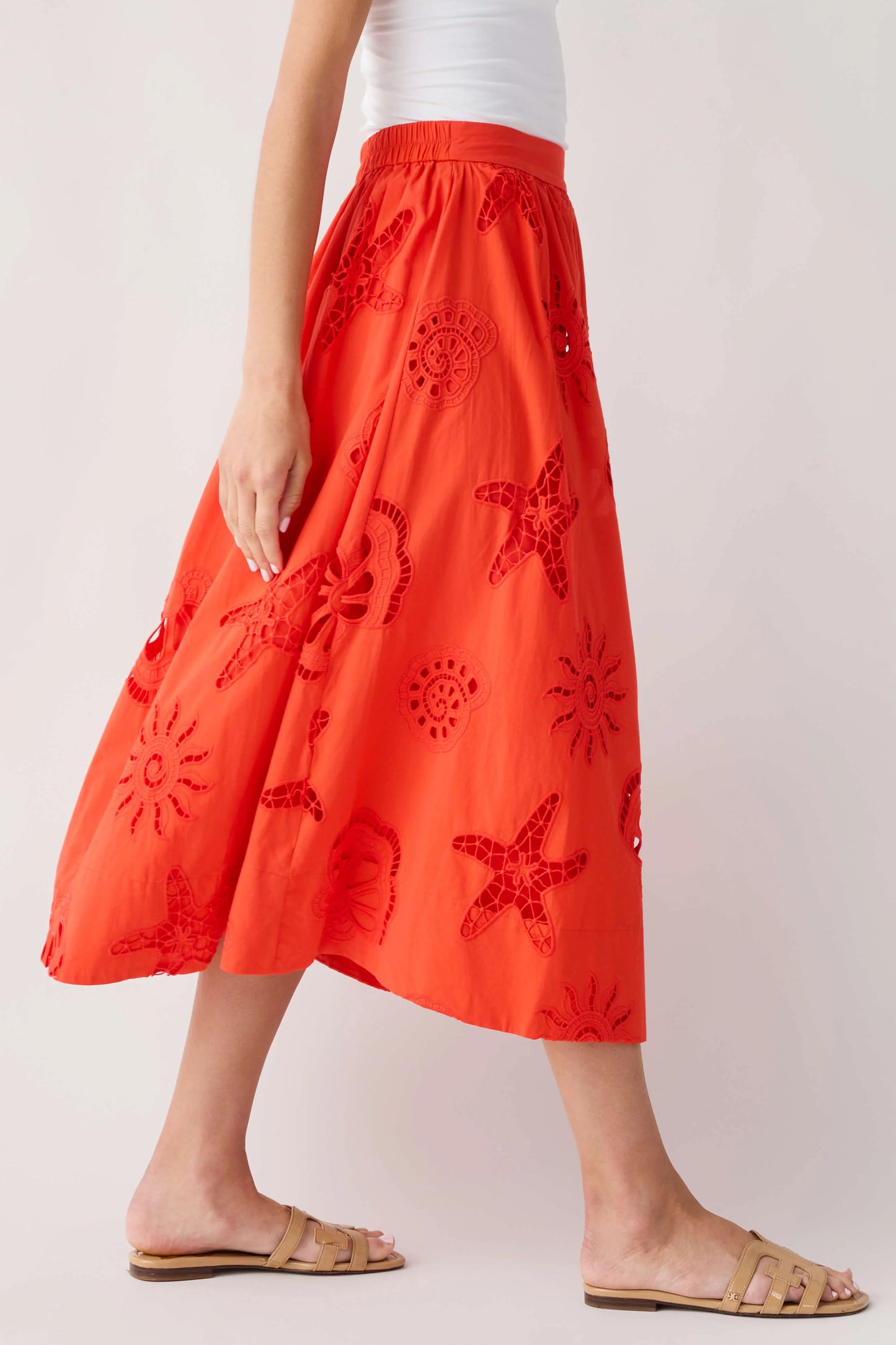 Person wearing a red skirt with starfish patterns on a plain background