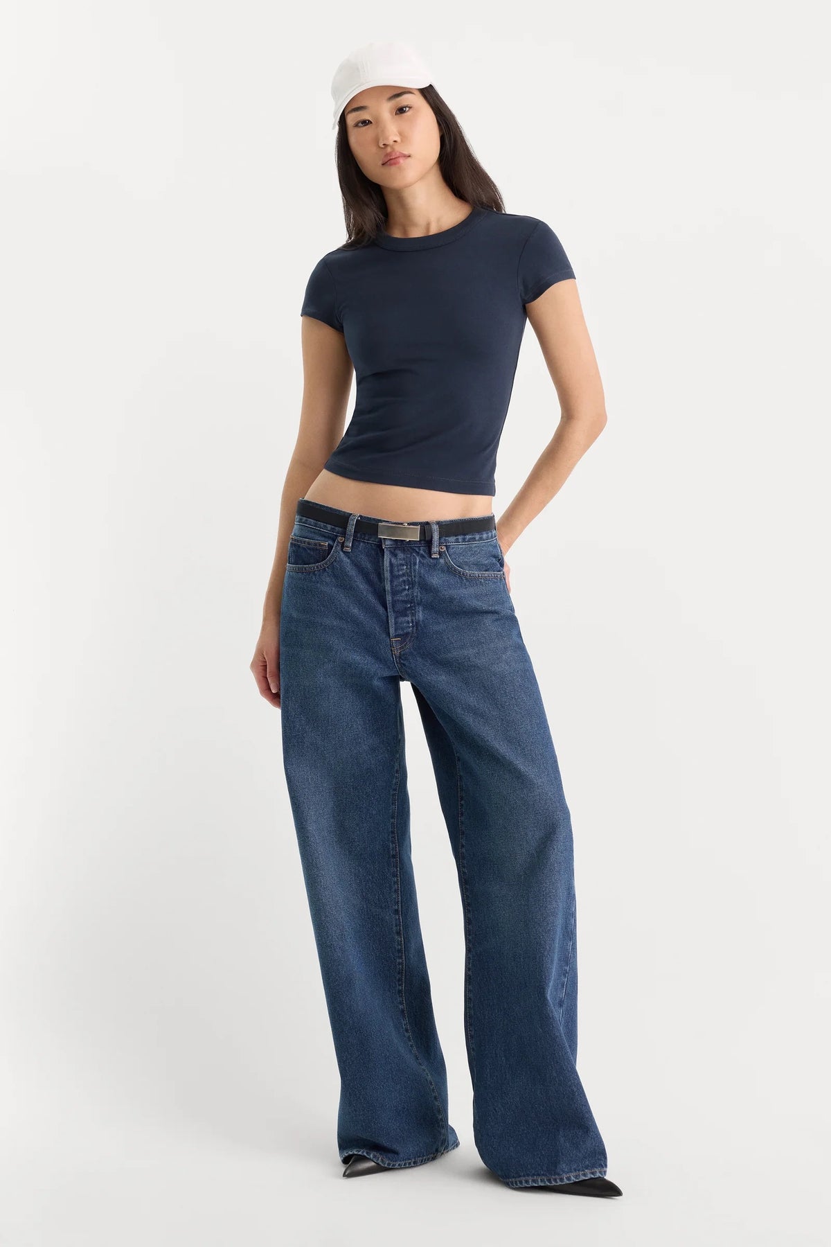 Woman wearing a navy t-shirt and blue jeans on a white background