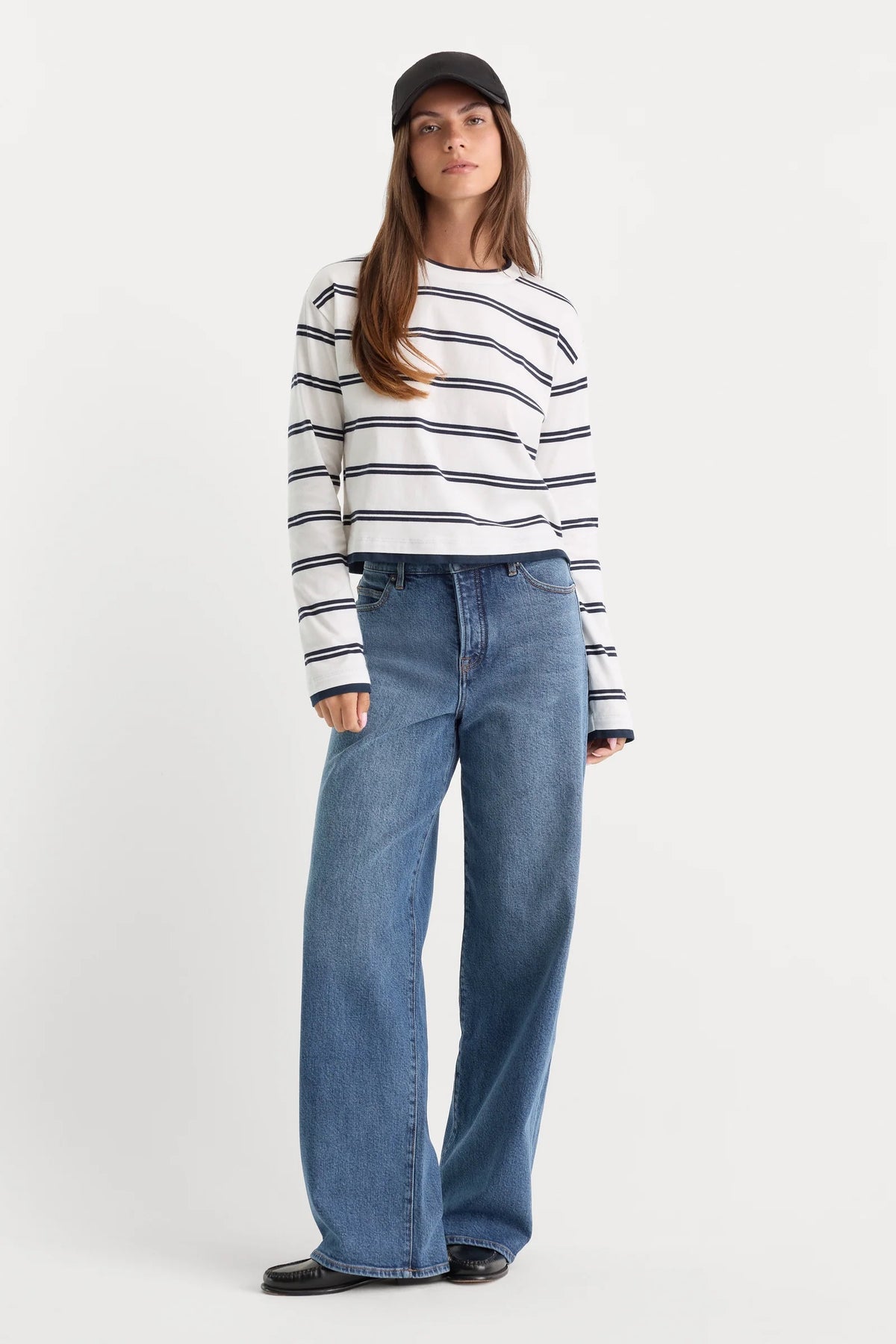 Woman wearing a striped sweater and blue jeans on a white background