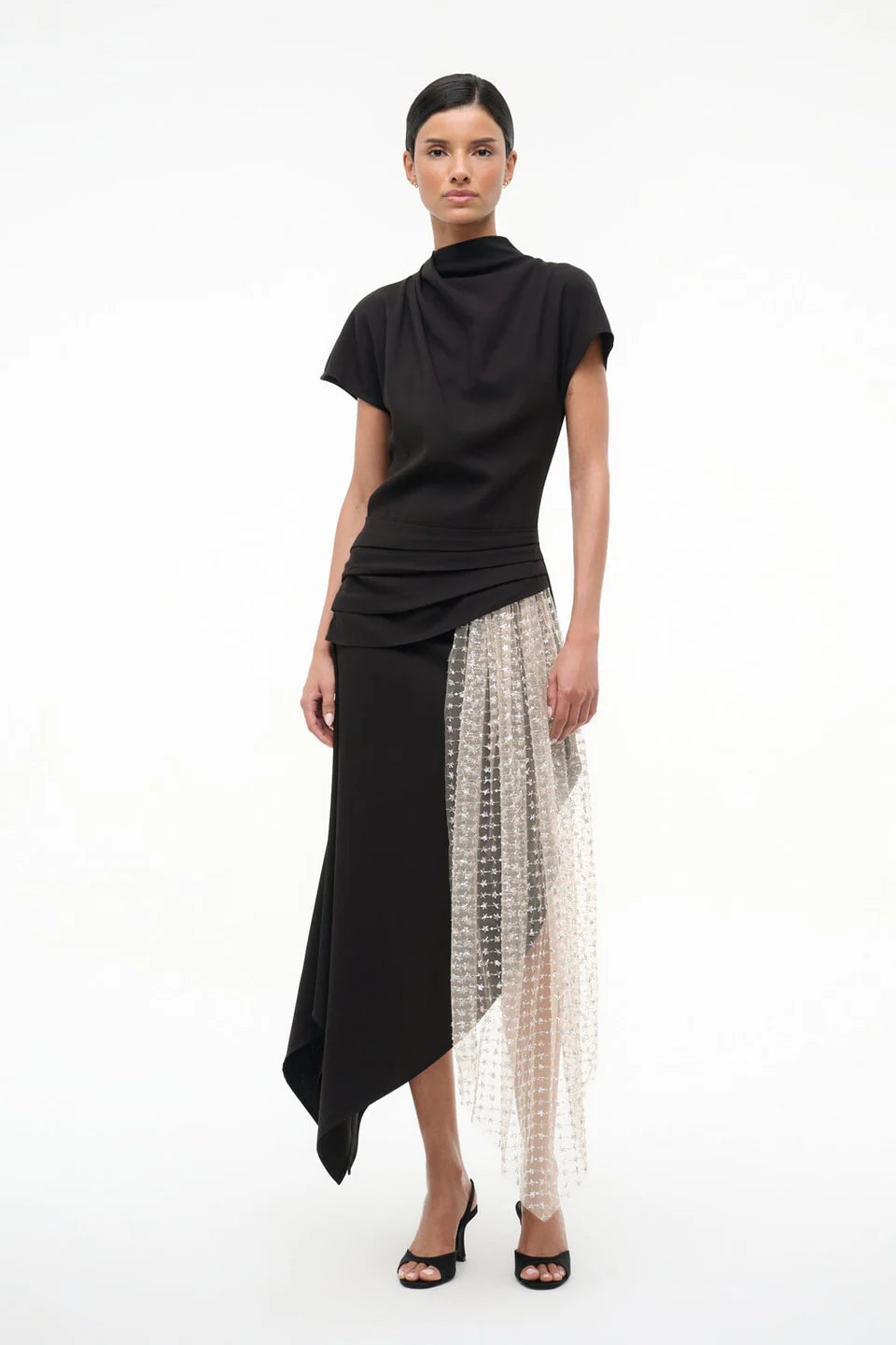 Woman wearing a black top and black and beige skirt on a white background