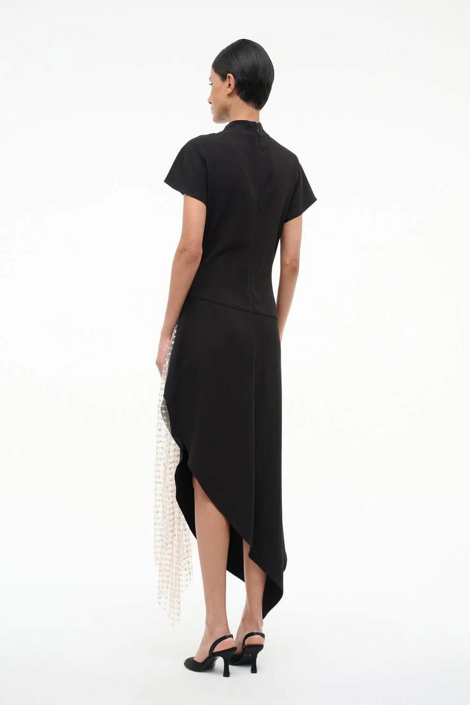 Woman wearing a black dress with a high-low hem on a white background