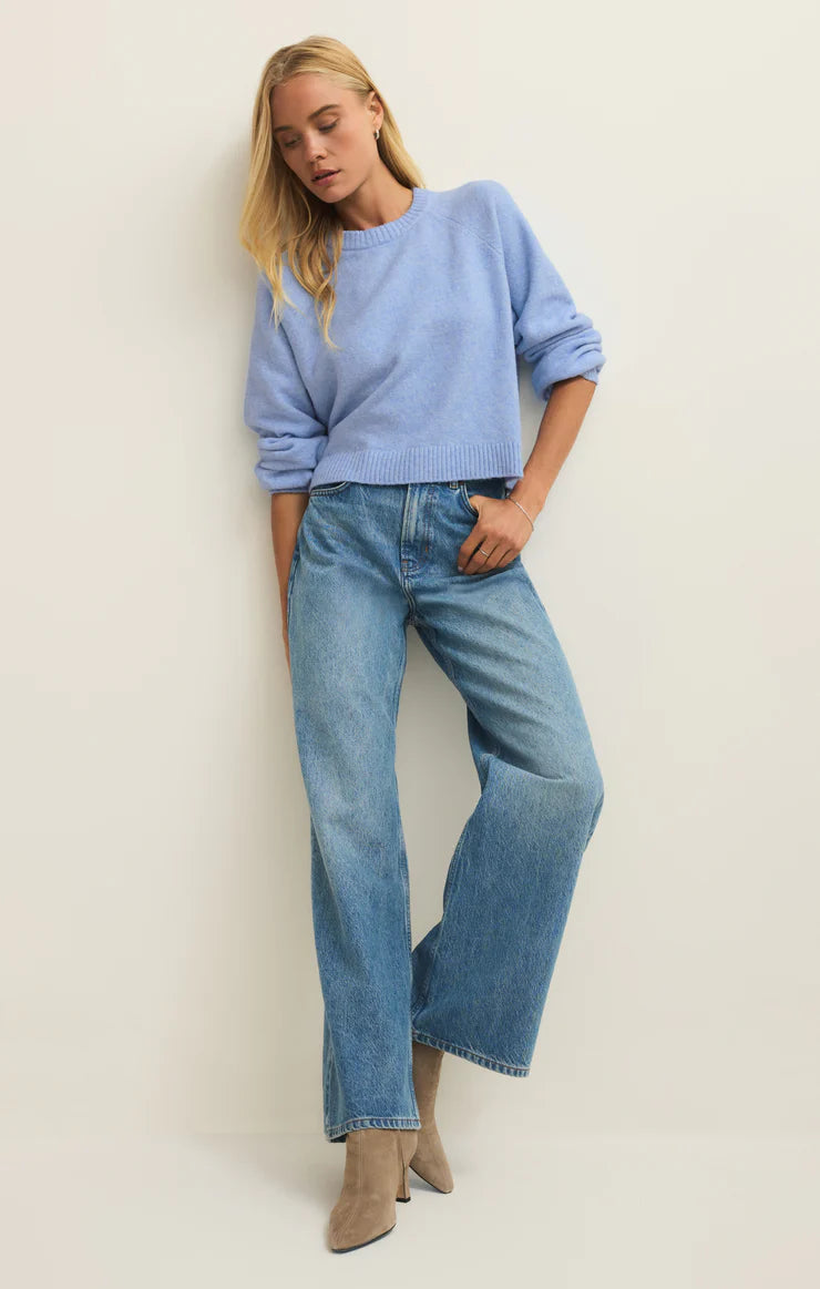 Woman wearing a light blue sweater and jeans against a plain background