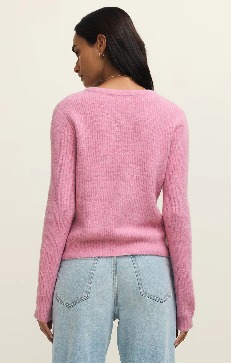Person wearing a pink sweater and light blue jeans on a beige background