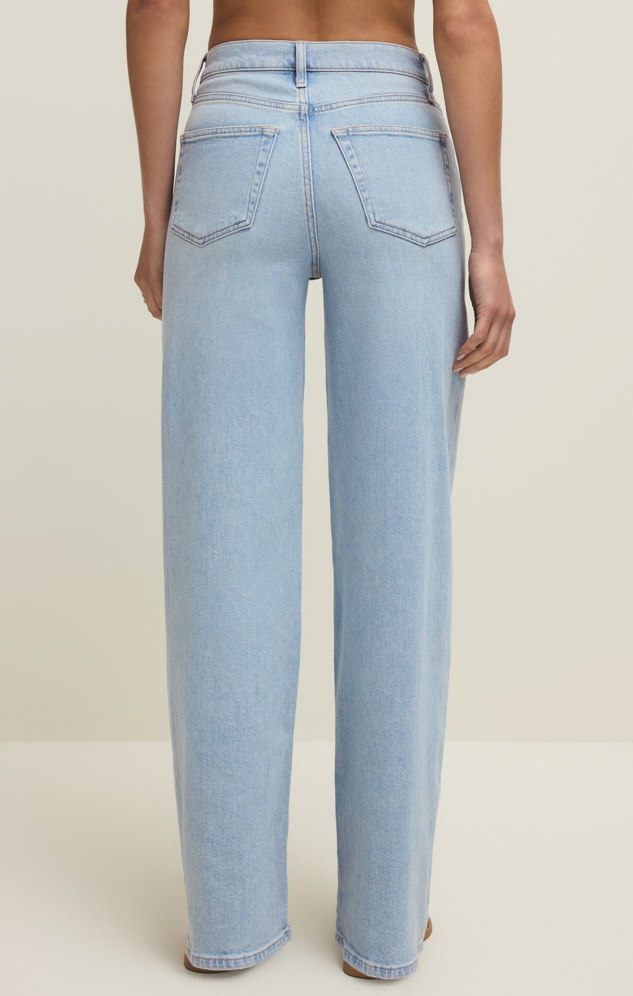 Light blue jeans worn by a person on a plain background