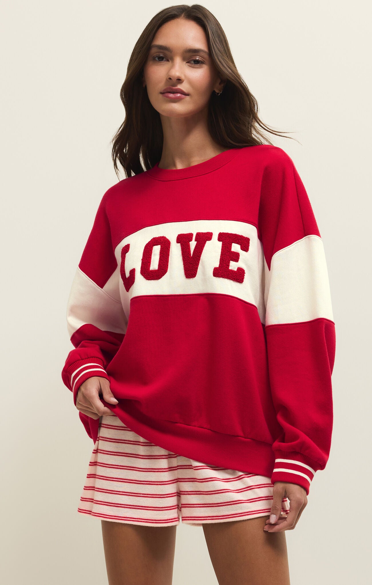 Woman wearing a red 'LOVE' sweater with white accents on a plain background