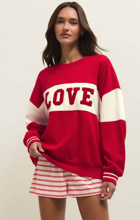 Woman wearing a red 'LOVE' sweater with white accents on a plain background