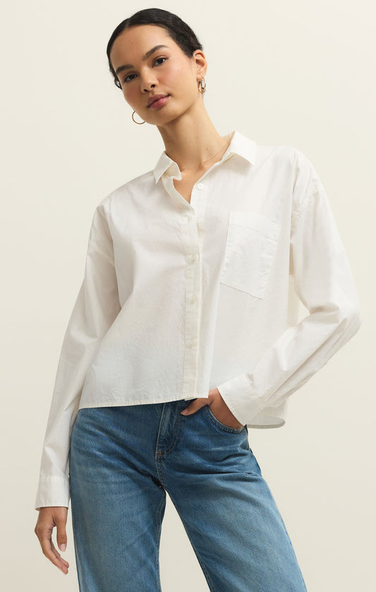 Woman wearing a white shirt and blue jeans against a plain background