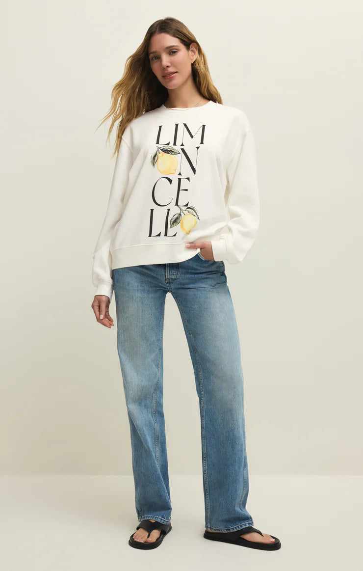 Woman wearing a white sweatshirt with text and graphics, paired with blue jeans on a plain background
