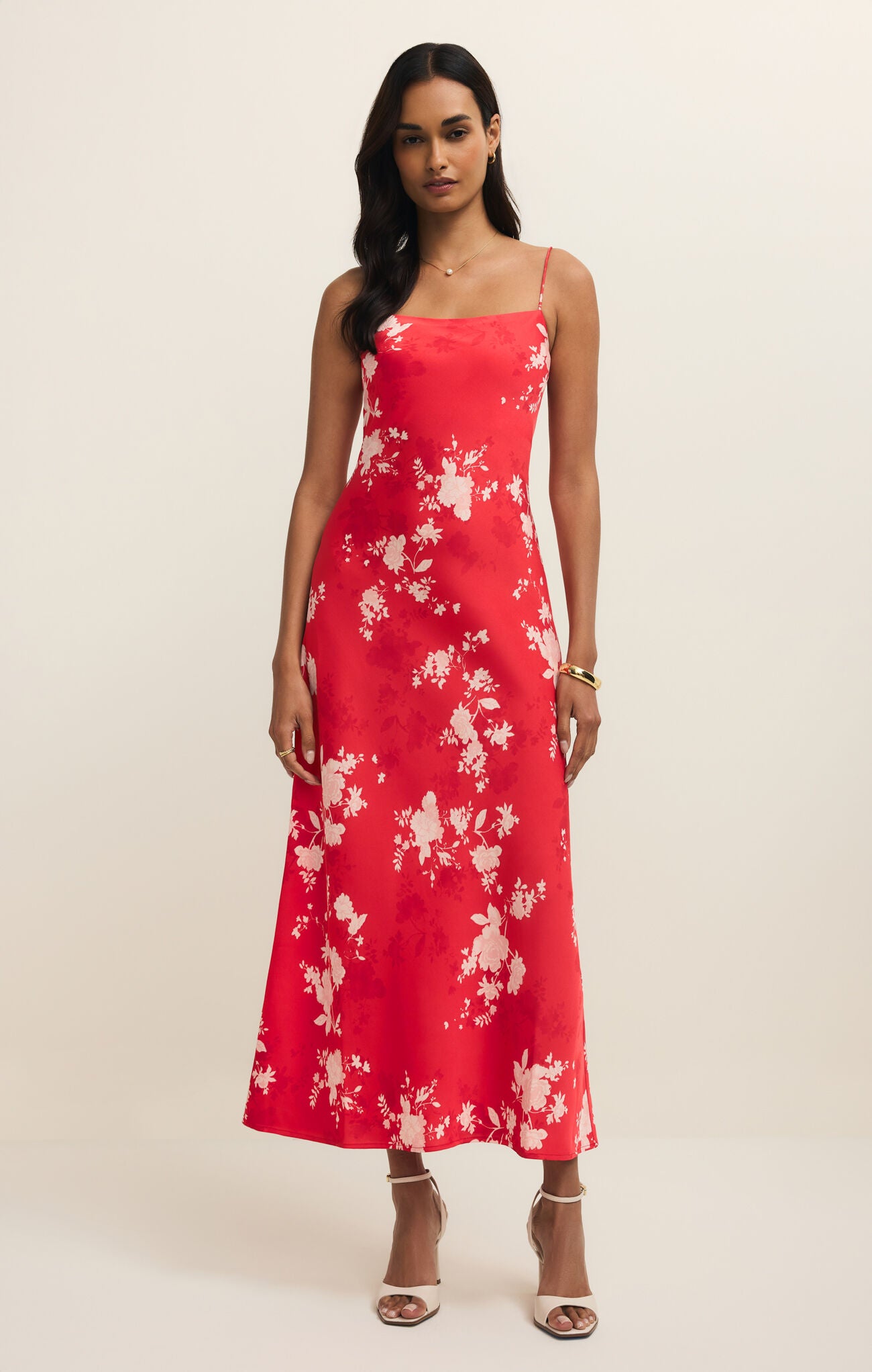 Woman wearing a red floral dress against a plain background