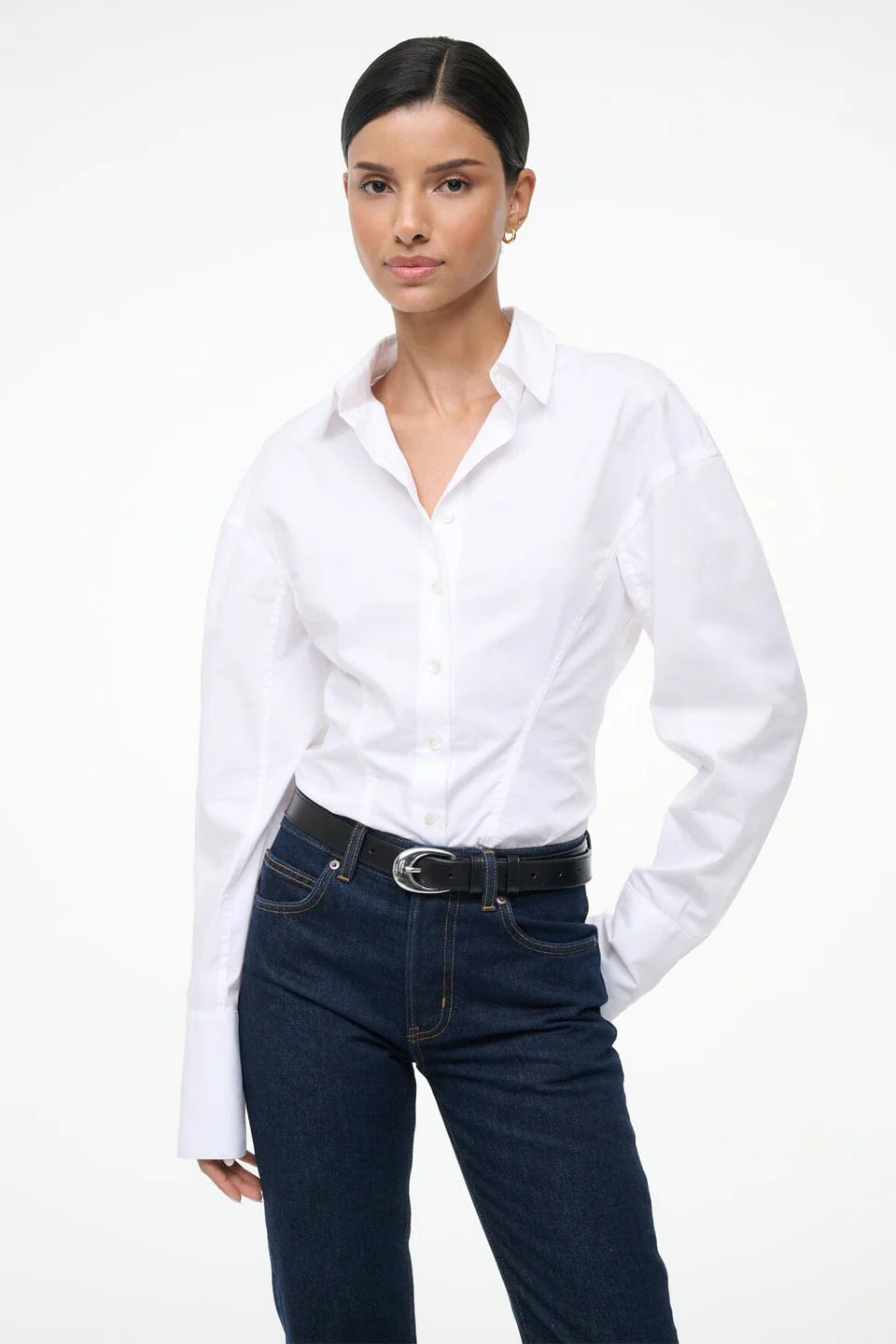 Woman wearing a white shirt and dark jeans on a white background