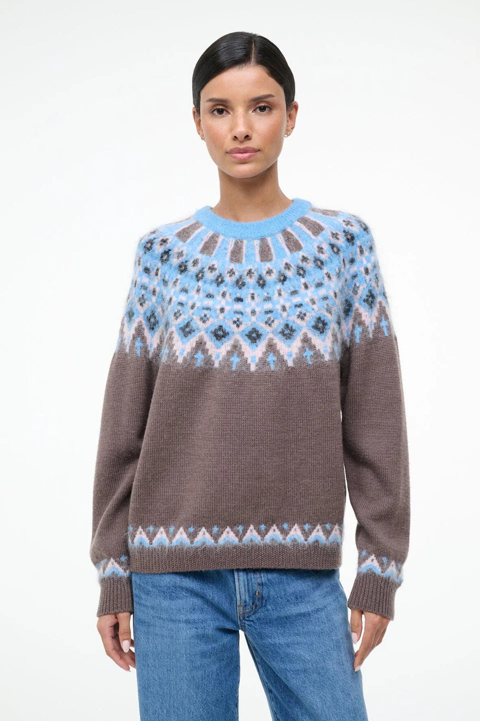 Woman wearing a patterned sweater with a blue and brown design on a white background