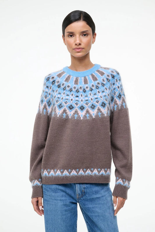 Woman wearing a patterned sweater with a blue and brown design on a white background