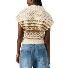 Person wearing a patterned beige sweater and blue jeans on a white background