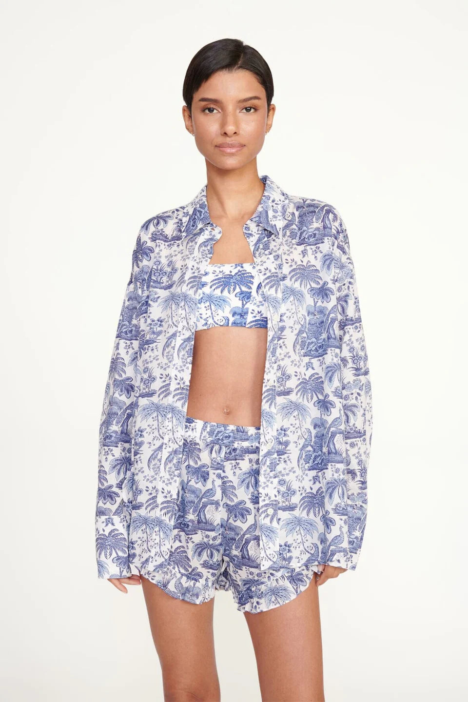 Woman wearing a blue floral shirt and shorts on a white background