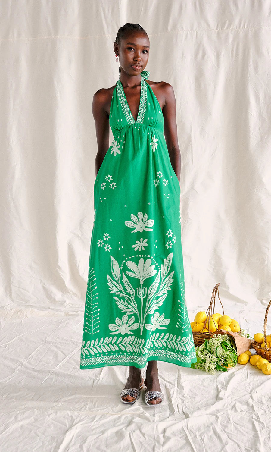 Woman wearing a green dress with white floral patterns on a white background