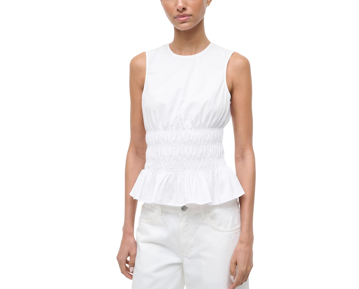 Woman wearing a white sleeveless peplum top and white pants on a white background