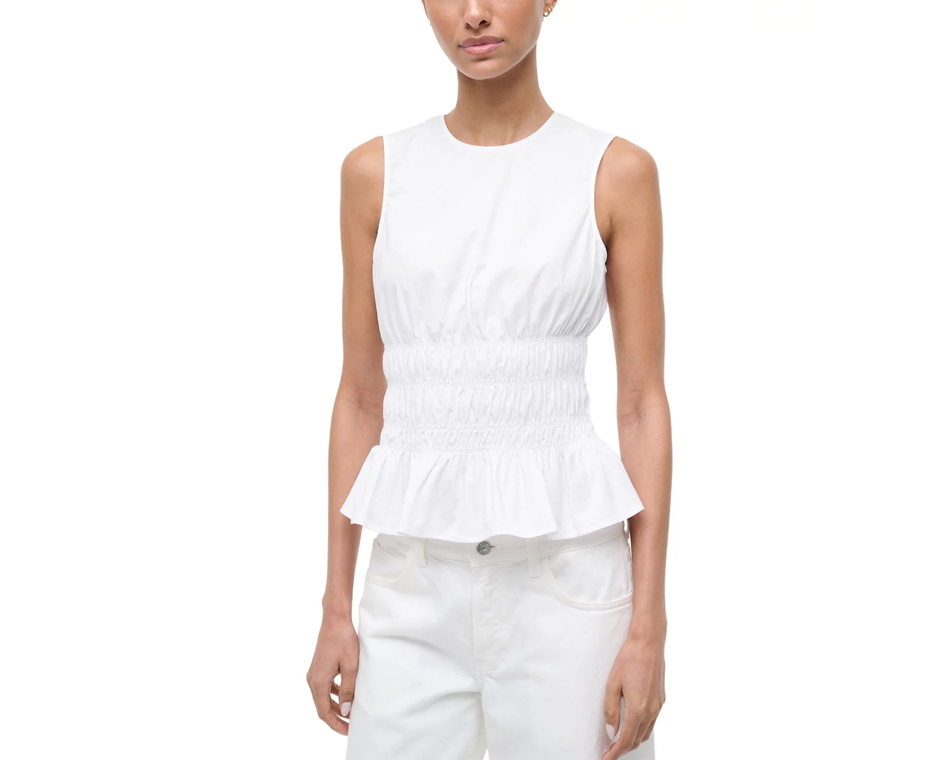 Woman wearing a white sleeveless peplum top and white pants on a white background