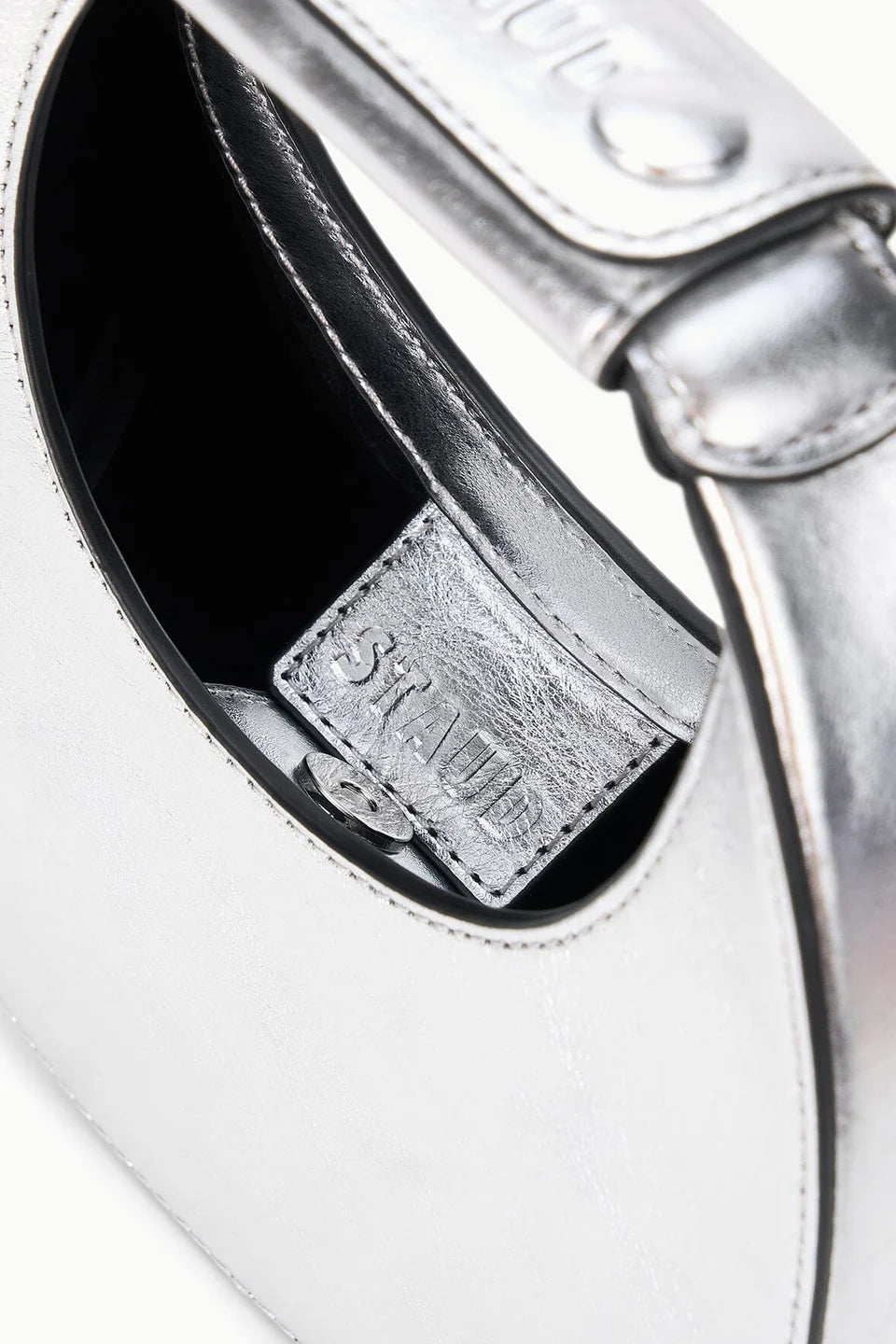 Close-up of a silver ring with 'Staud' branding on a white background