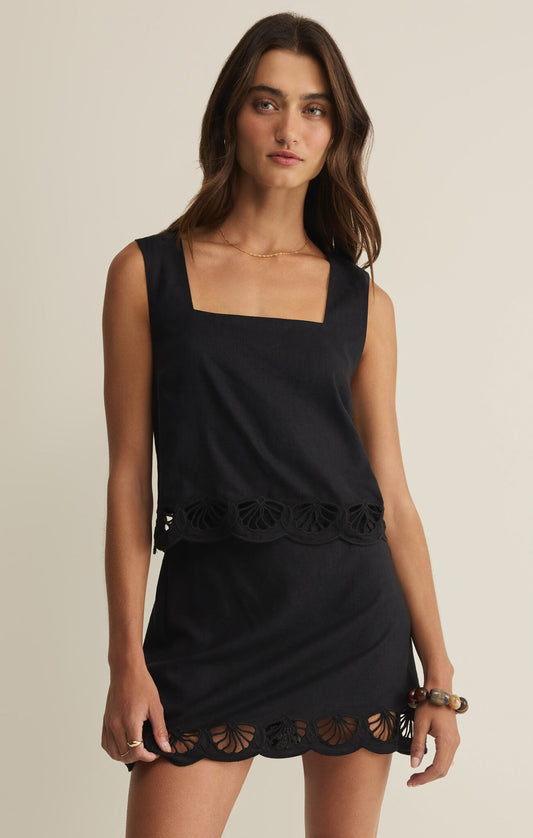 Woman wearing a black dress with lace details on a beige background