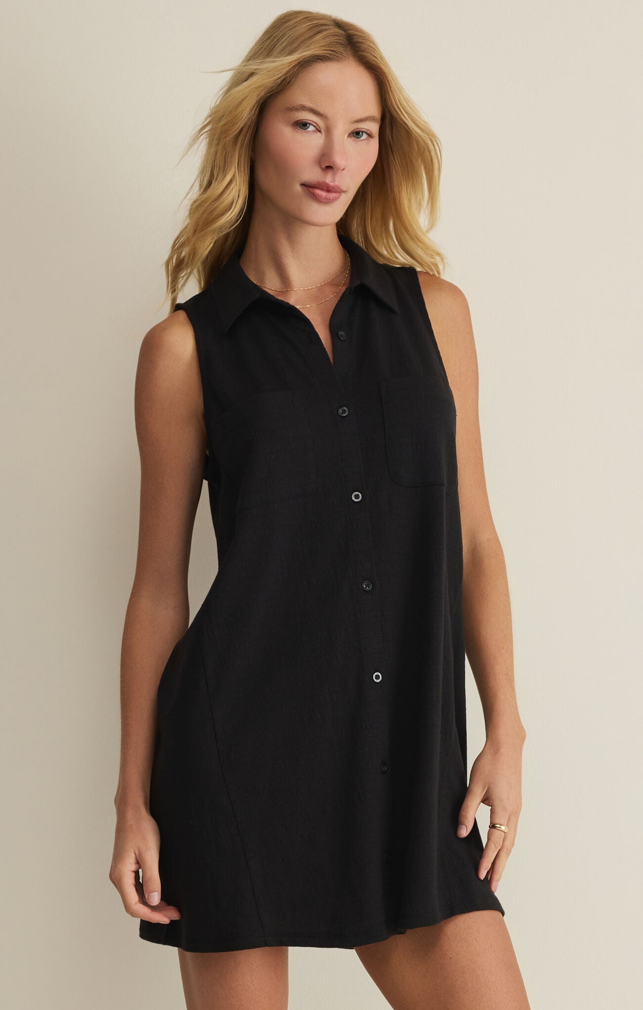 Woman wearing a black sleeveless dress against a beige background