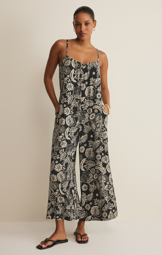 Woman wearing a black and white floral patterned jumpsuit on a beige background