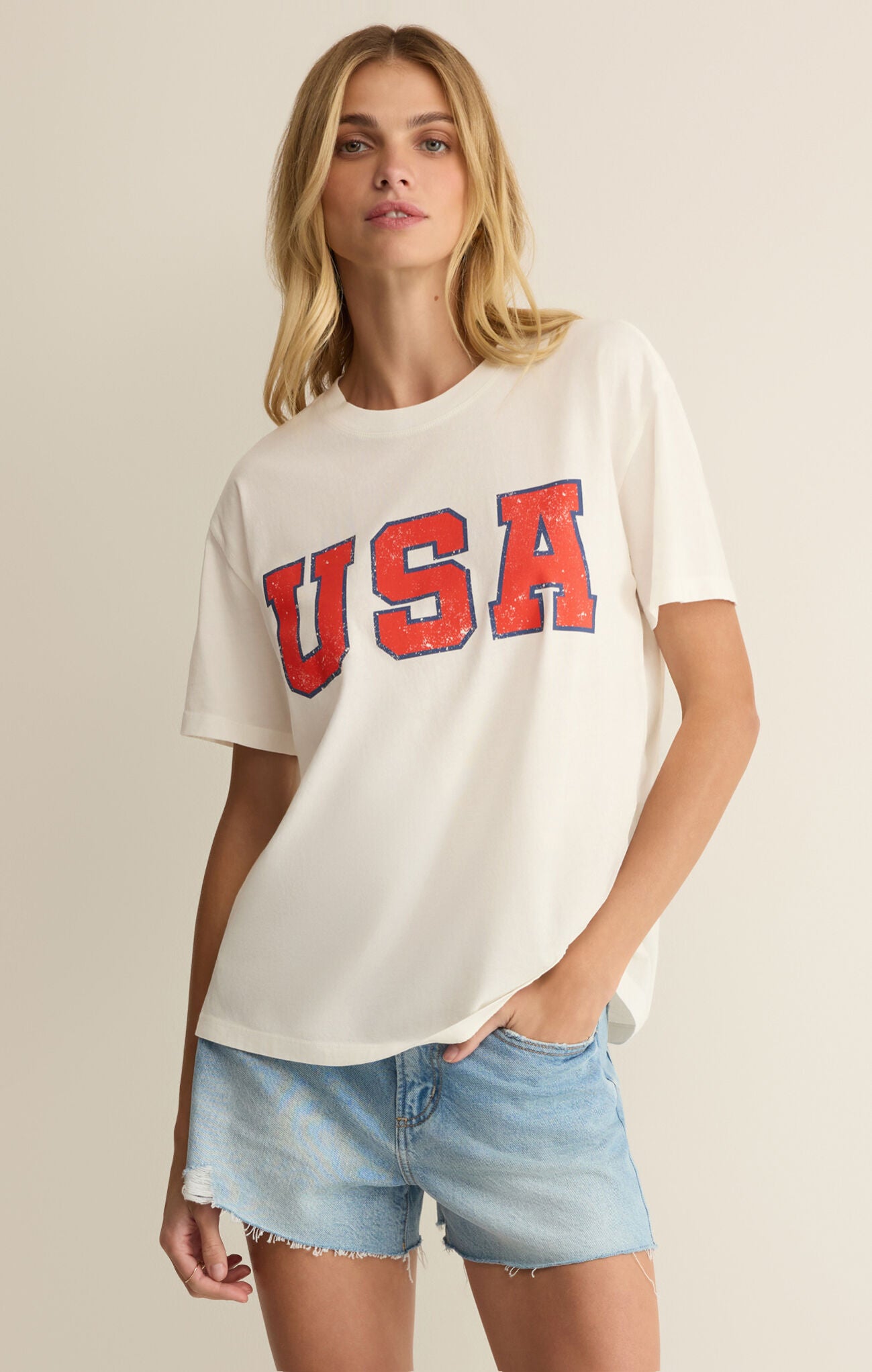 Woman wearing a white t-shirt with 'USA' printed in red on a beige background