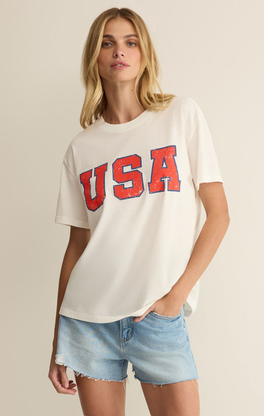 Woman wearing a white t-shirt with 'USA' printed in red on a beige background