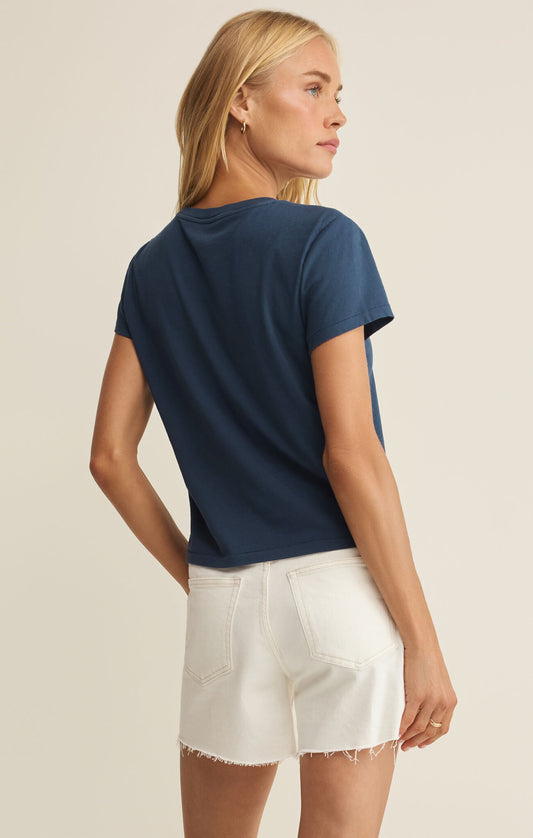 Woman wearing a navy blue t-shirt and white shorts on a beige background
