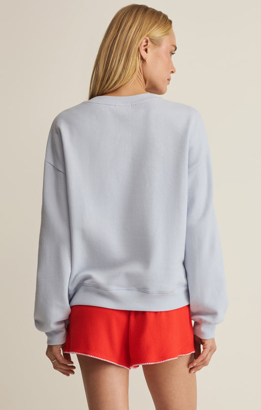 Person wearing a light blue sweatshirt and red shorts on a beige background