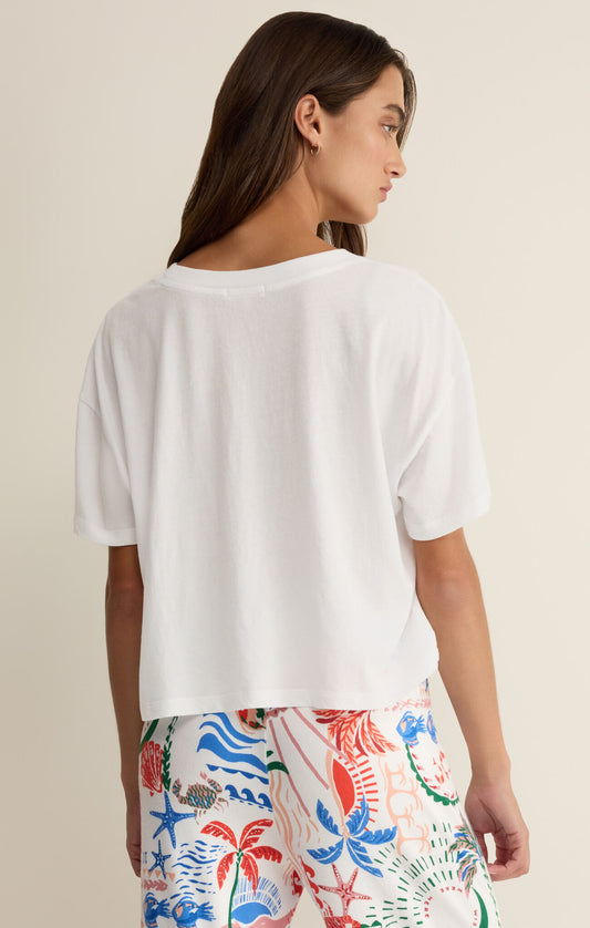 Woman wearing a white t-shirt and colorful floral pants on a beige background