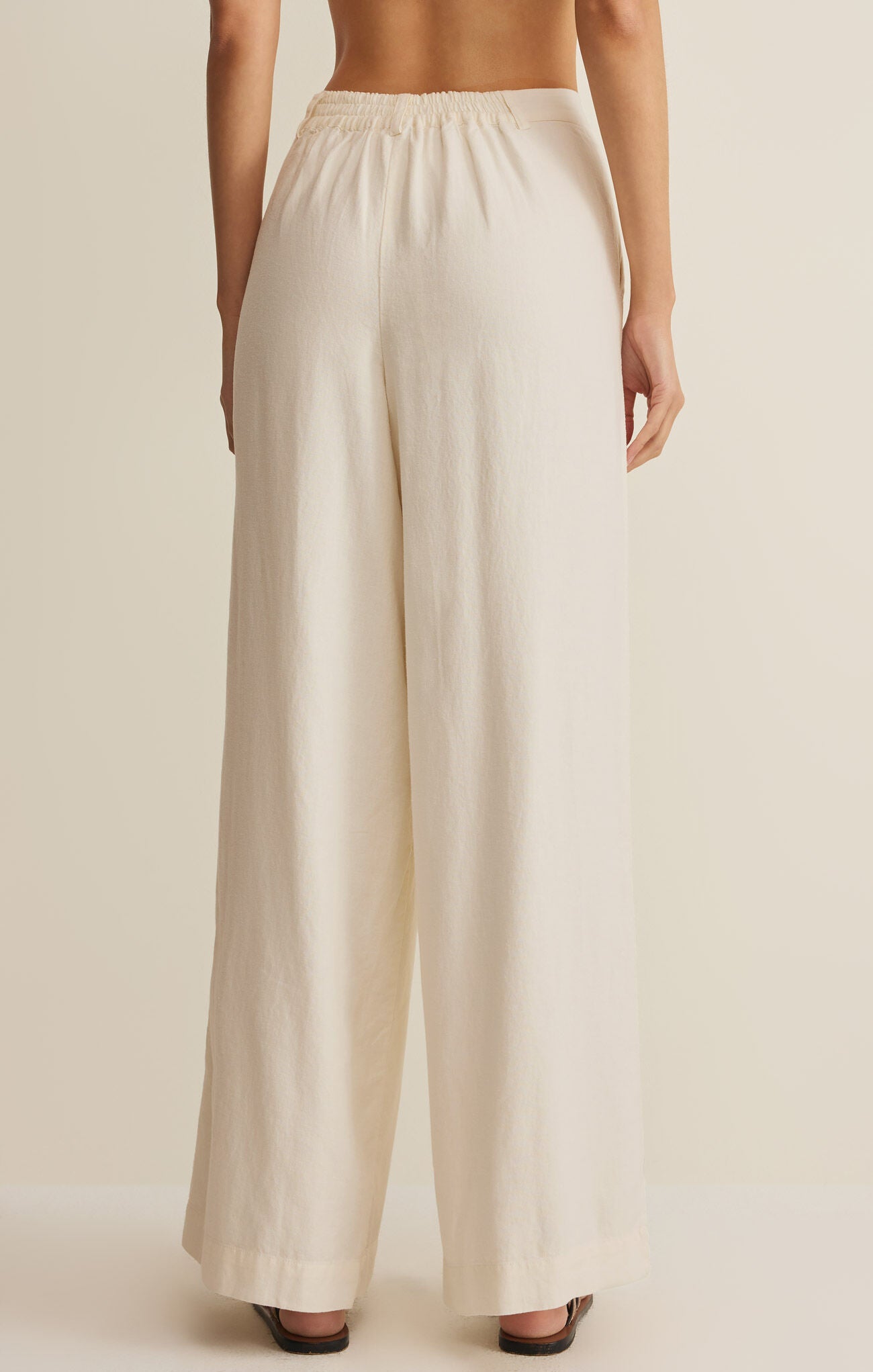 Beige wide-leg pants worn by a person on a beige background