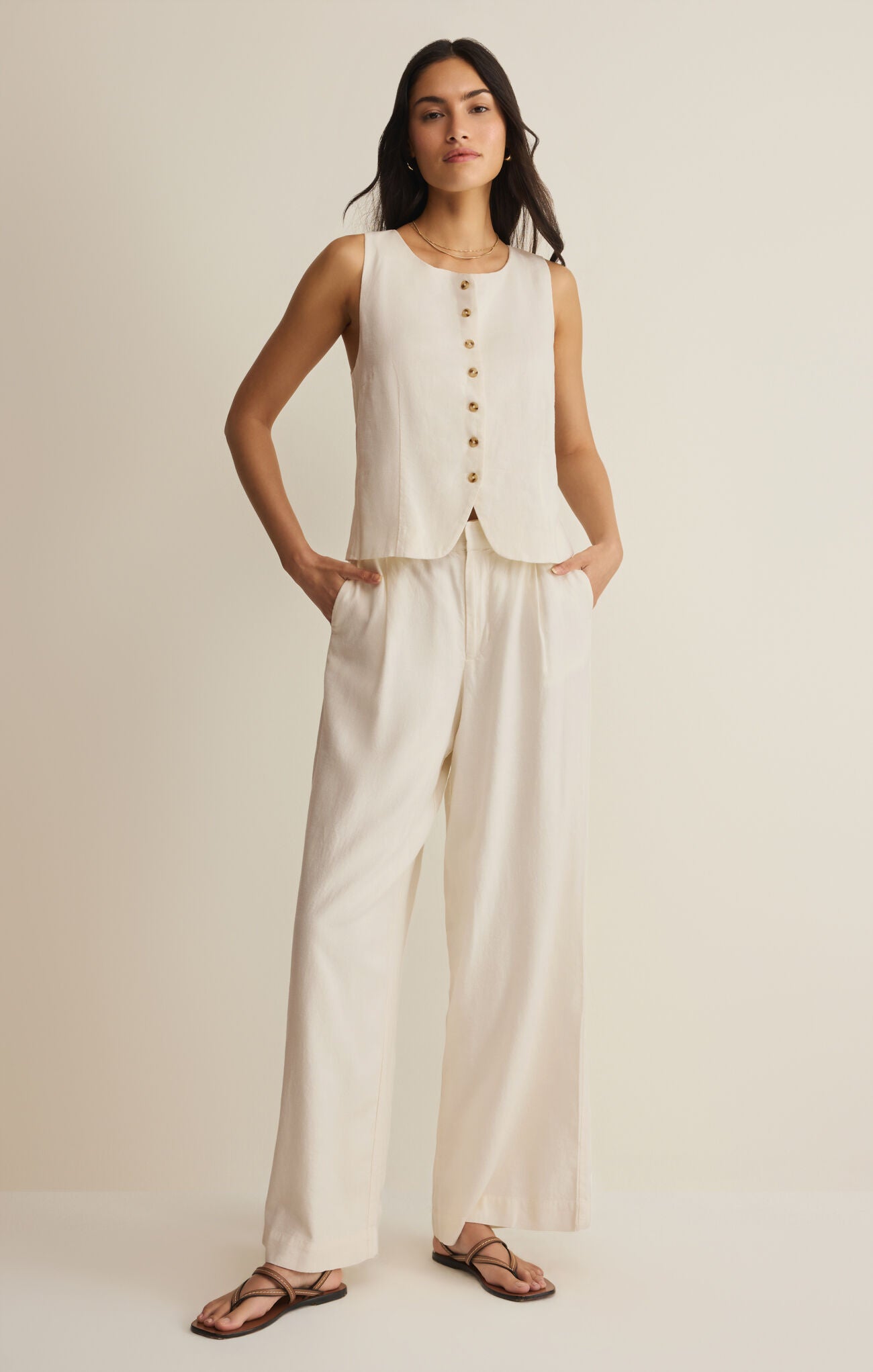 Woman wearing a sleeveless top and wide-leg pants on a plain background