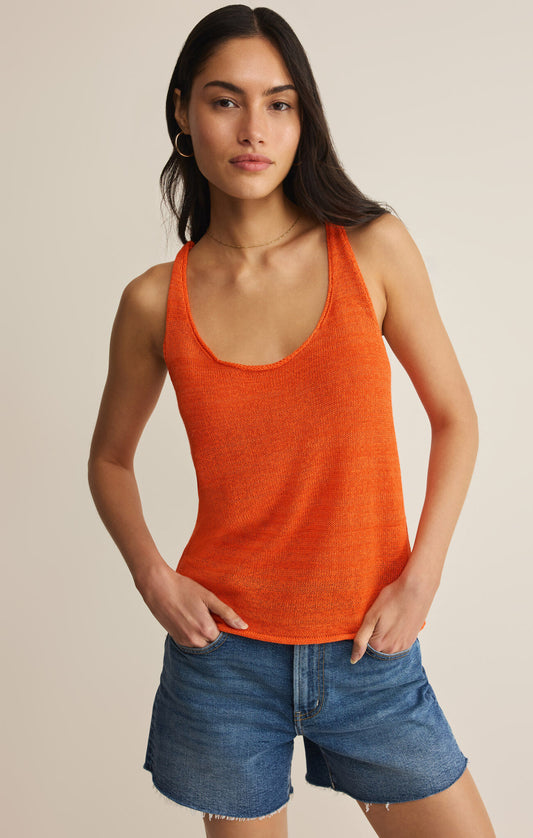 Woman wearing an orange tank top and denim shorts on a beige background