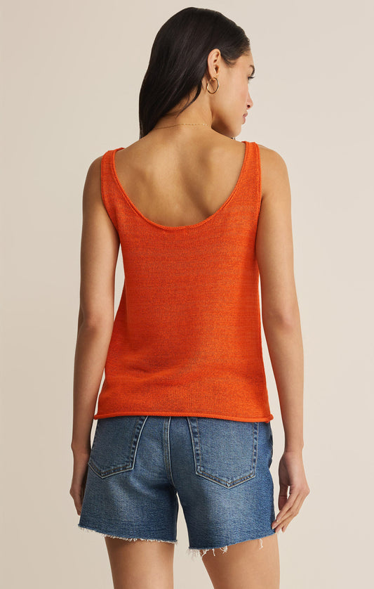 Woman wearing an orange tank top and blue denim shorts on a beige background
