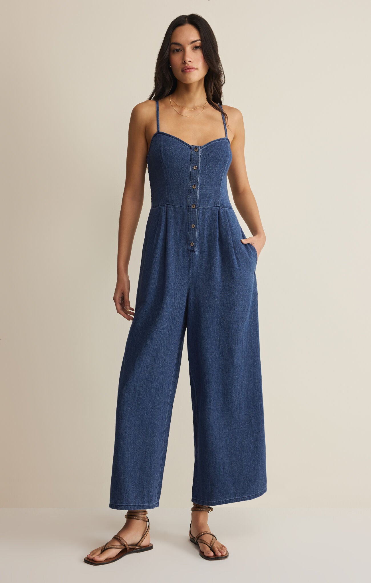 Woman wearing a blue jumpsuit on a beige background