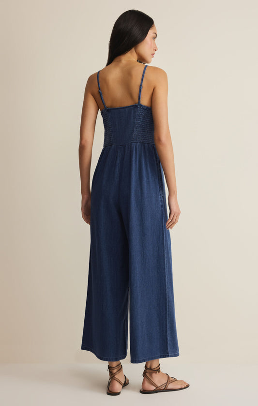 Woman wearing a blue jumpsuit on a beige background