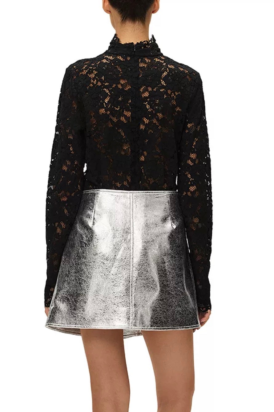 Person wearing a black lace top and silver metallic skirt on a white background