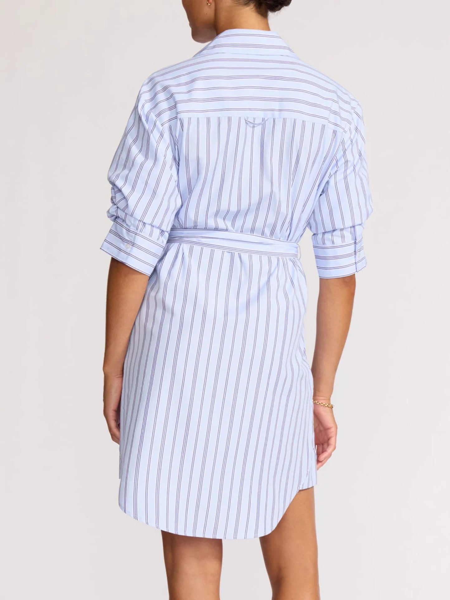 Person wearing a blue and white striped dress on a plain background