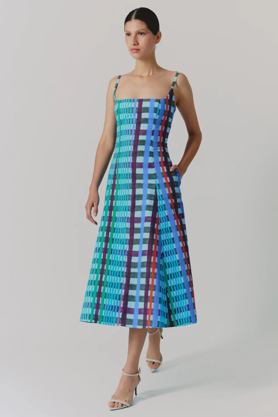 Woman wearing a colorful plaid dress on a plain background