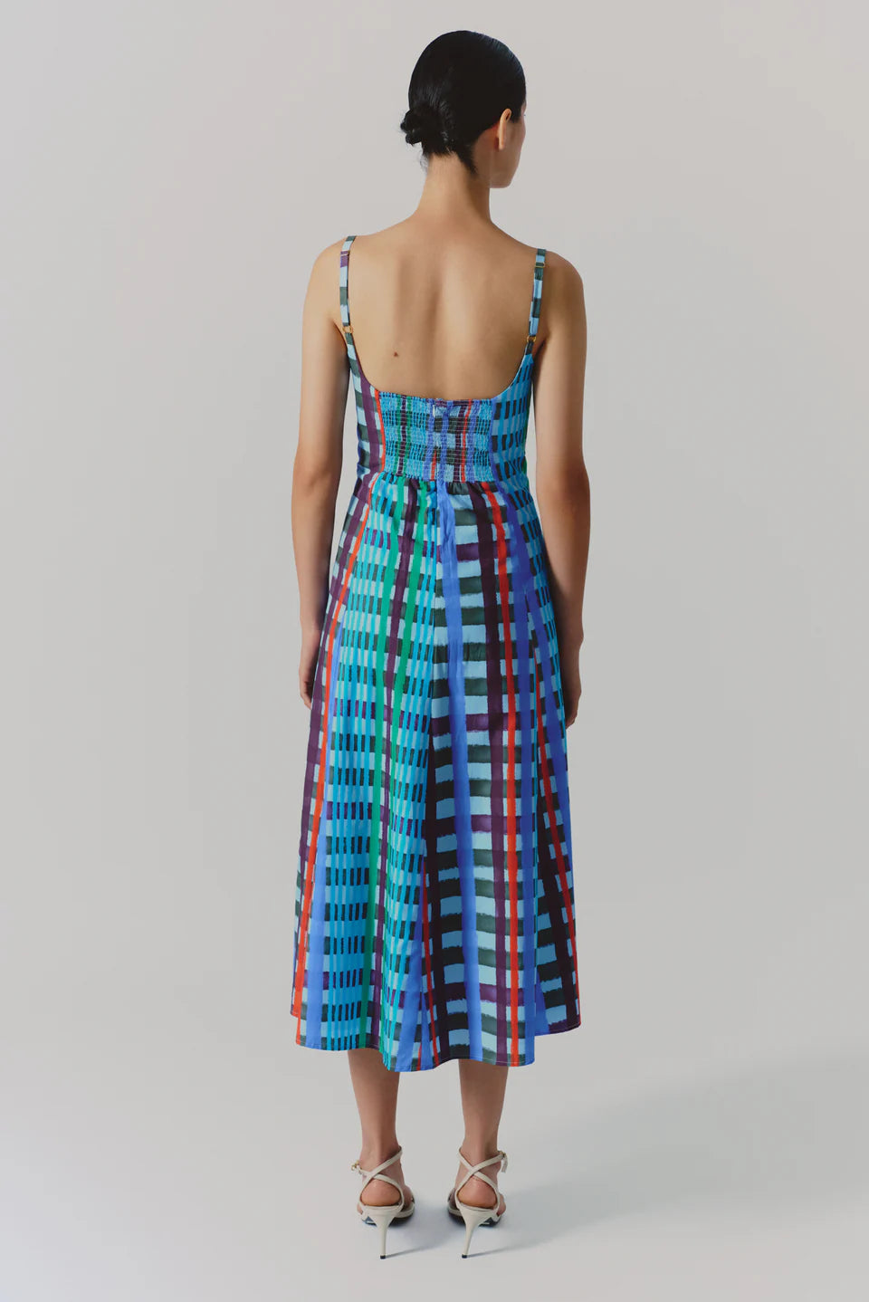 Woman wearing a colorful patterned dress on a plain background