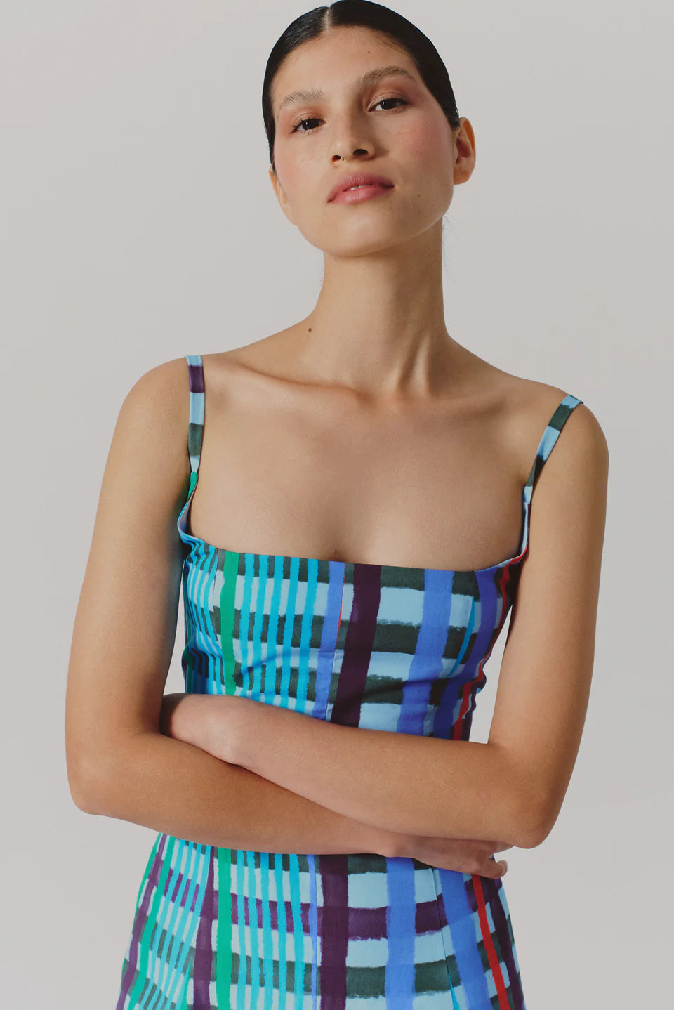 Woman wearing a colorful plaid dress against a plain background