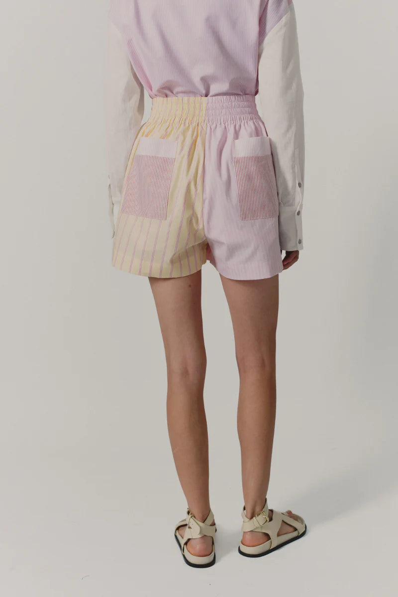 Person wearing a light pink top and colorful shorts on a white background