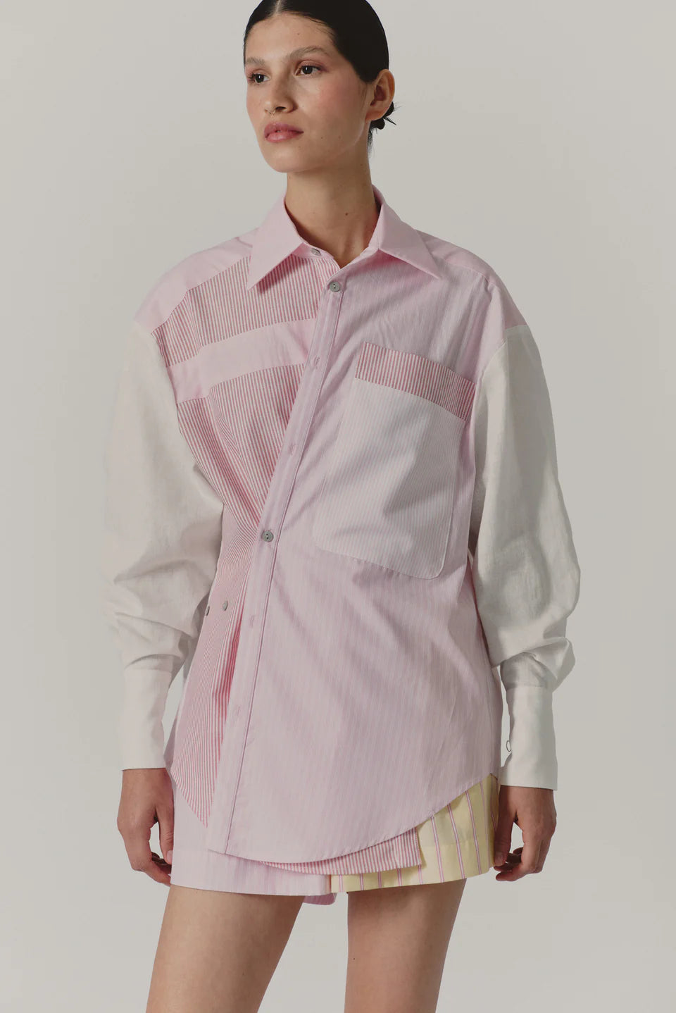 Woman wearing a pink and white checkered shirt over a white shirt with a plain background