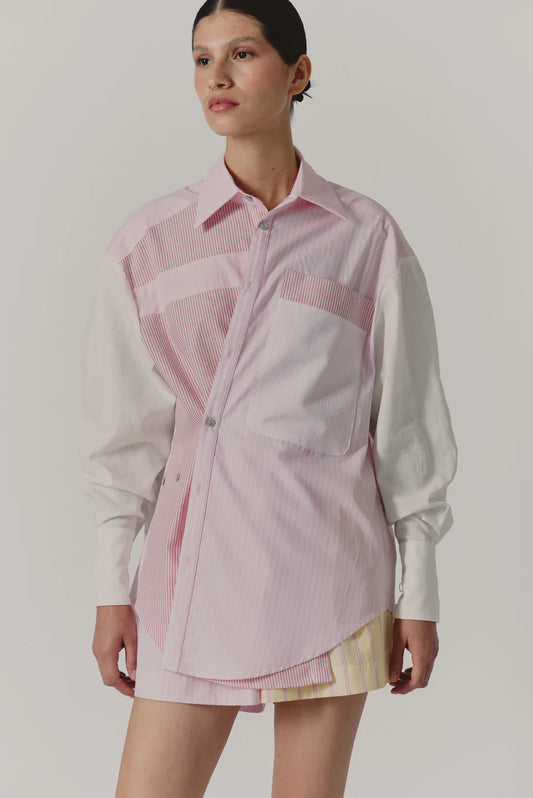 Woman wearing a pink and white checkered shirt over a white shirt with a plain background
