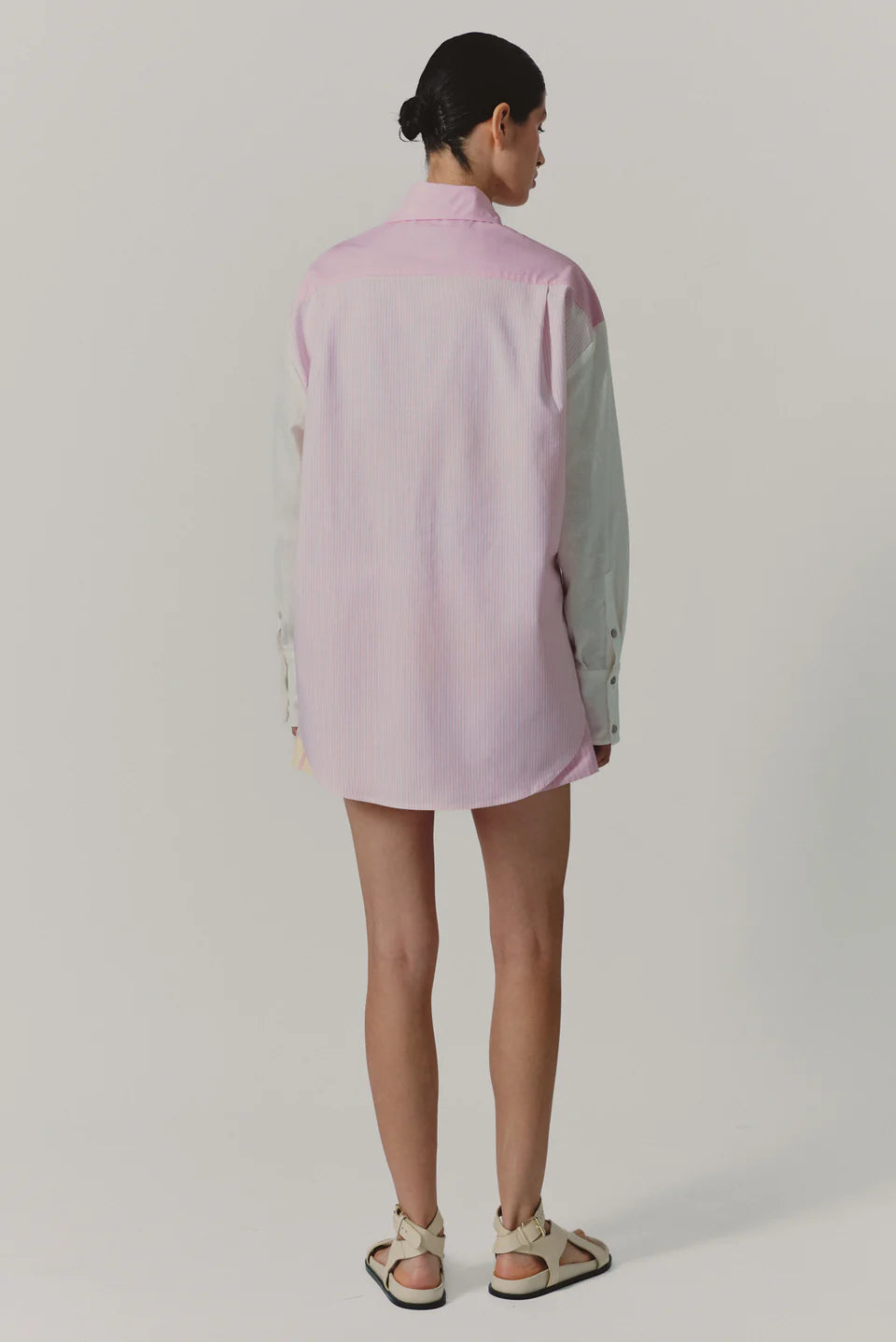 Person wearing a light pink shirt with long sleeves on a plain background