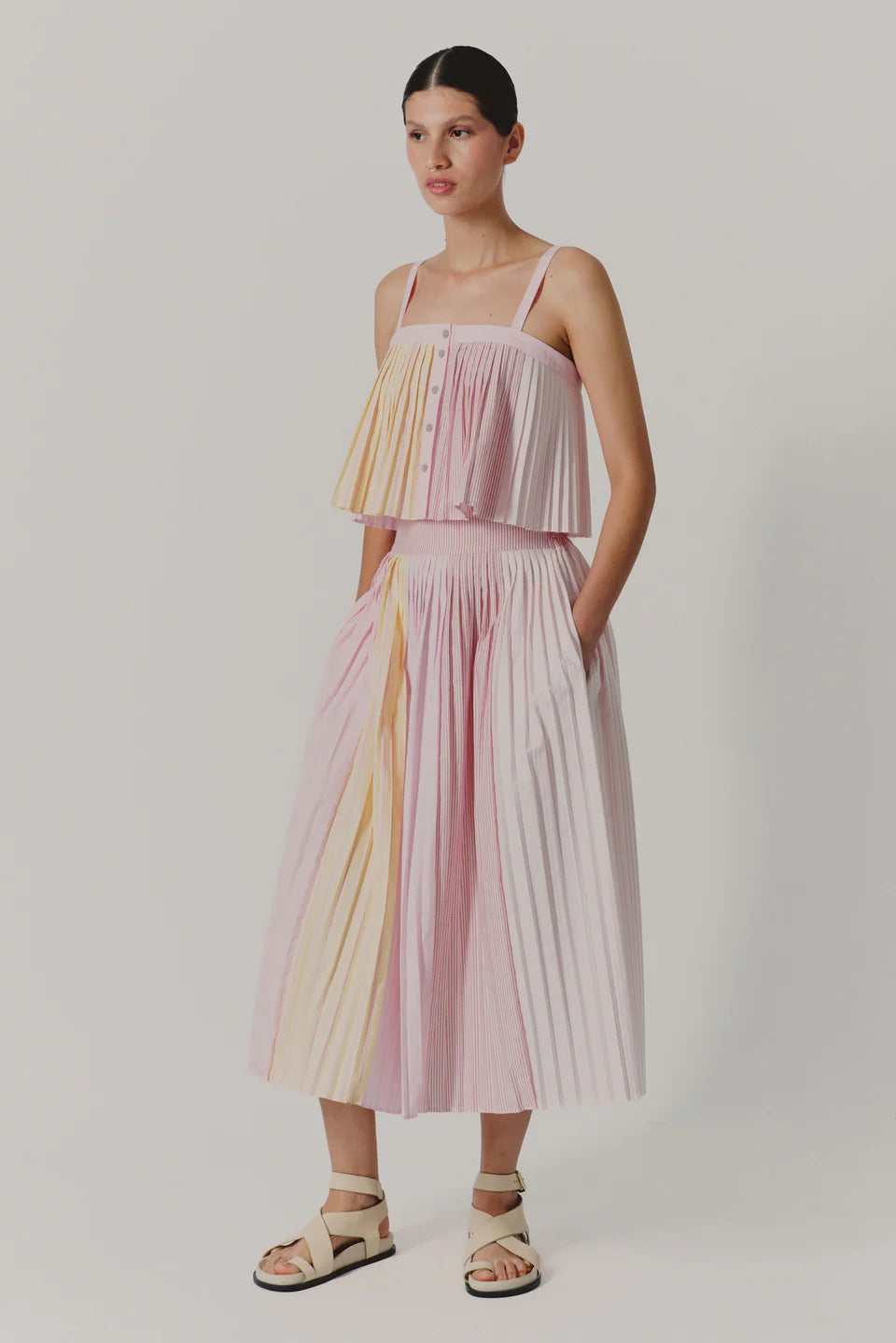 Woman wearing a pastel striped dress on a plain background