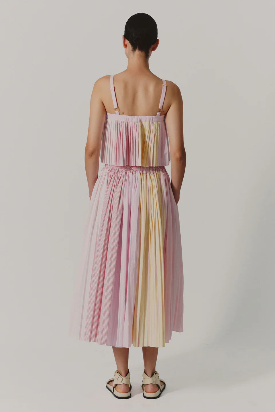 Woman wearing a pastel striped dress on a plain background