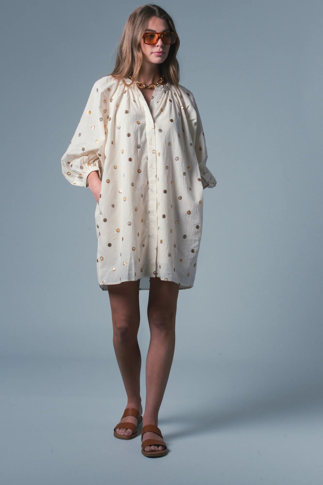 Woman wearing a light-colored dress with a subtle pattern on a gray background