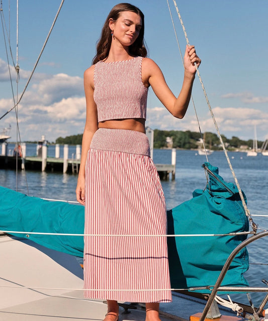 Woman in a pink outfit standing on a boat with water and sky in the background